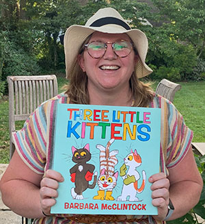 smiling librarian holding Three Little Kittens book